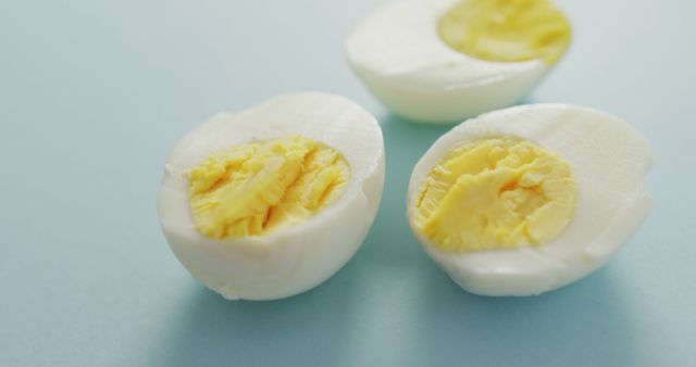 Image of close up of three egg halves on blue background. fusion food, eggs and easter concept.