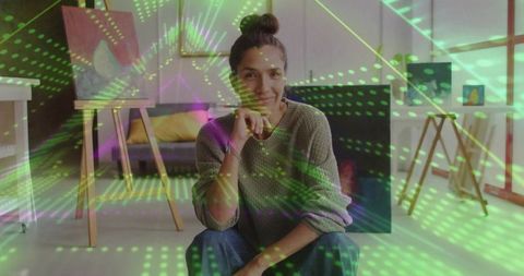 Woman artist sitting in bright home studio with canvas, easel and light projection