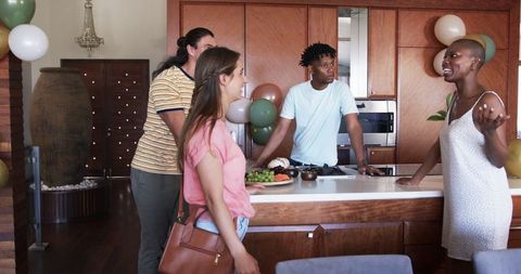 Friends Socializing in Modern Kitchen Setting During Casual Gathering