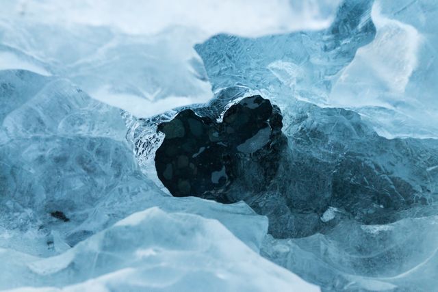 This image shows a unique heart-shaped ice formation in a winter landscape. The crystal-clear, bluish ice provides a stunning natural texture. Ideal for use in publications related to natural wonders, winter themes, environmental conservation, and love symbols.