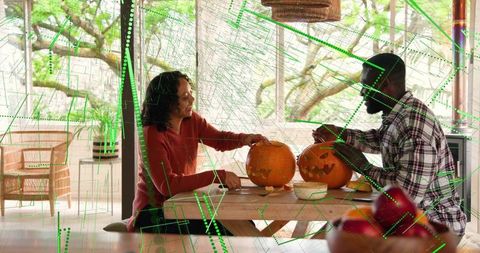 Couple carving pumpkins on sunroom table for cozy autumn craft and halloween decor