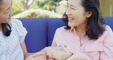 Joyful gift exchange between woman and young girl outdoors