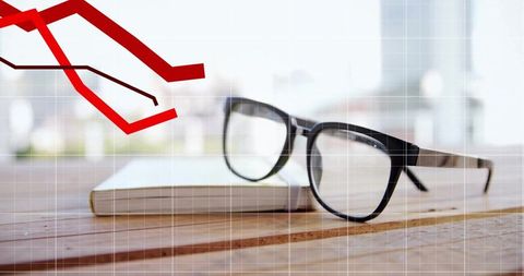 Black-rimmed glasses and book on wooden desk with financial chart overlay