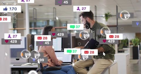 Collaborating colleagues discussing project with social notifications in open-plan office