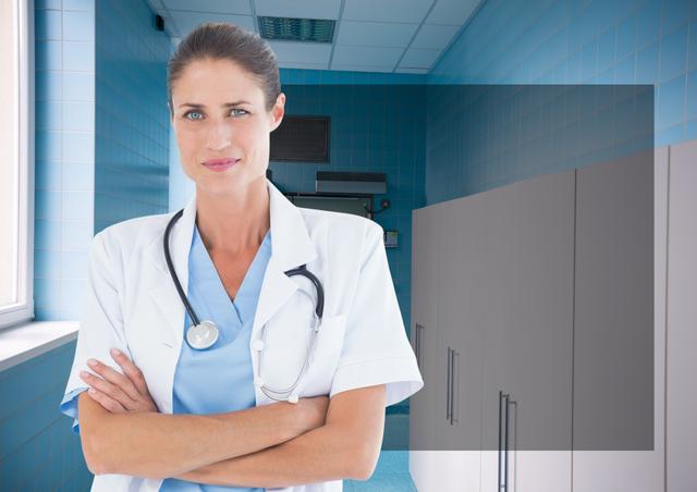 Confident female doctor stands with arms crossed in a hospital corridor. She is wearing blue scrubs and a white lab coat with a stethoscope around her neck. The hospital environment in the background with cabinets conveys a sense of professionalism and modern healthcare. Perfect for medical and healthcare promotions, hospital advertisements, medical education materials, and healthcare-related website content.