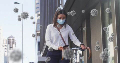 Masked urban commuter walking bicycle while checking phone amid airborne virus particles