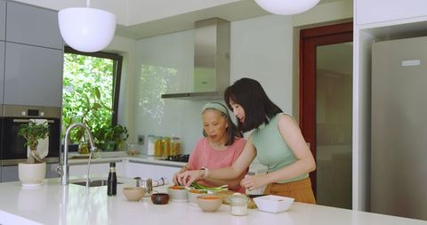 Mother and Adult Daughter Cooking Together in Modern Kitchen