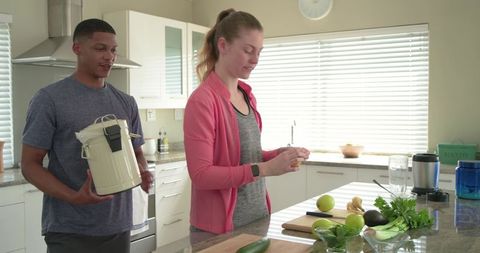 Couple preparing healthy meal on modern kitchen island with fresh produce and fitness tracker