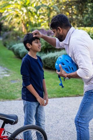 Indian Father Adjusting Son's Bicycle Helmet for Safe Riding