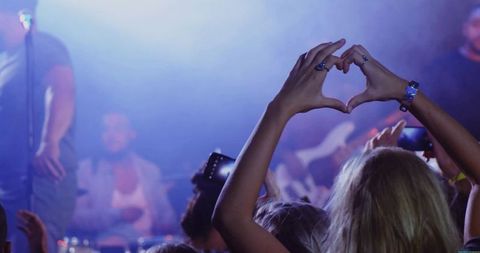 Heart Gesture Showing Adoration at Live Concert with Vibrant Stage Lights