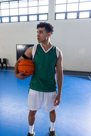Young Male Basketball Player Holding Ball on Indoor Court