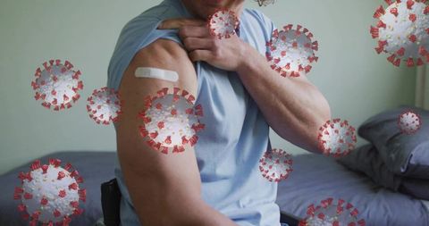 Man revealing vaccination bandage on upper arm with coronavirus overlay and wheelchair