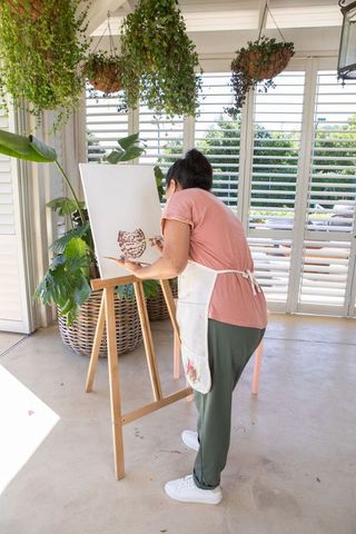 Creative Woman Painting Botanical Ceramic Design in Sunlit Studio