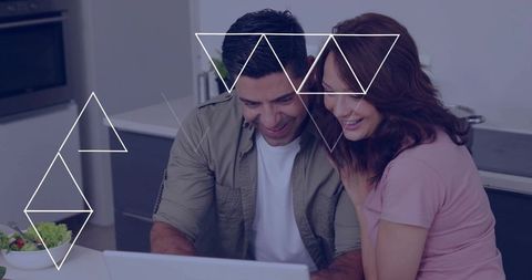 Couple leaning over laptop in kitchen planning meals and managing finances together