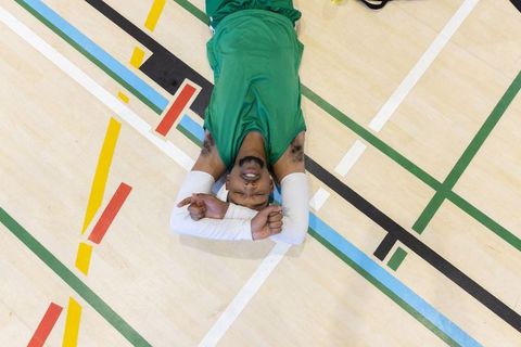 Overhead african american basketball player resting on gym floor with colorful court lines