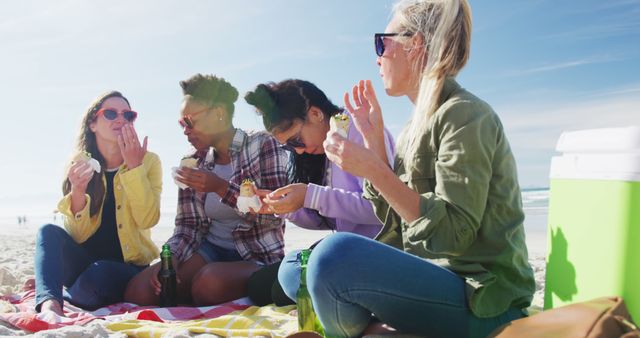 Happy group of diverse female friends having fun, having picnic at the beach. holiday, freedom and leisure time outdoors.