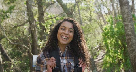 Smiling Woman Enjoying Hike in Sunlit Forest