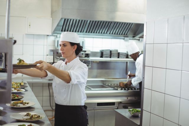 Female chef keeping appetizer plate ready on the order station at restaurant
