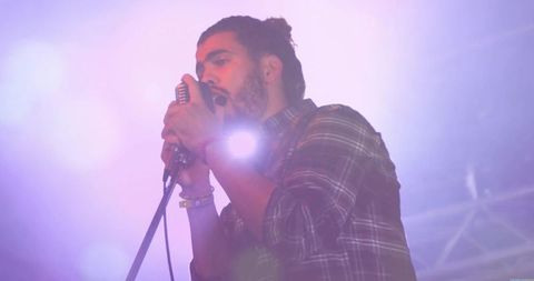 Musician Performing on Stage with Vintage Microphone in Concert Atmosphere