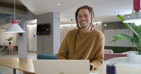 Smiling African American Freelancer Working on Laptop in Modern Coworking Lounge