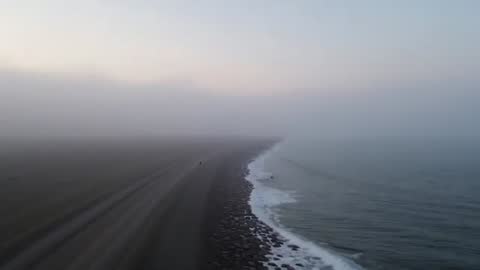 Drone Gliding Over Misty Beach with Solitary Walker at Dawn
