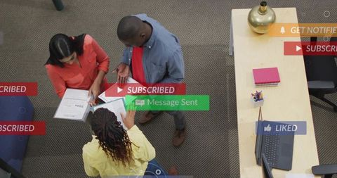 Overhead view of diverse team collaborating in office workspace with social media overlays
