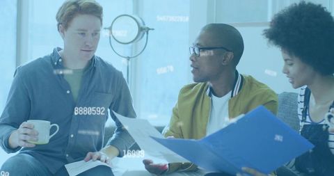 Coworkers Reviewing Documents on Couch in Casual Office Lounge Discussing Data and Analytics