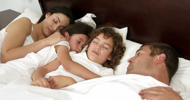 Family members are sleeping together in bed, showing comfort and closeness. This image can be used for themes related to family bonds, love, nighttime routines, or promoting products and services related to sleep, bedding, family well-being, and parenting.