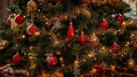 Glowing Christmas tree with red baubles, warm white lights, gold garland and wrapped gifts