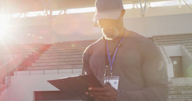 Male Coach with Clipboard in Outdoor Sports Stadium During Sunset - Download Free Stock Images Pikwizard.com