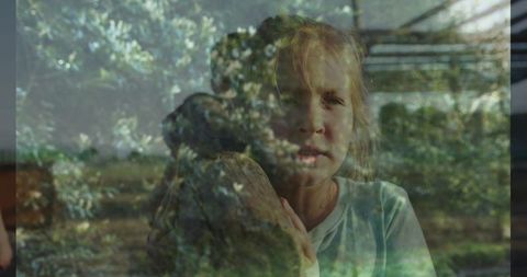 Young girl holding stone in greenhouse surround by nature