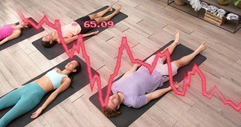 Group practicing guided supine relaxation on mats with ecg heart rate overlay 65.09