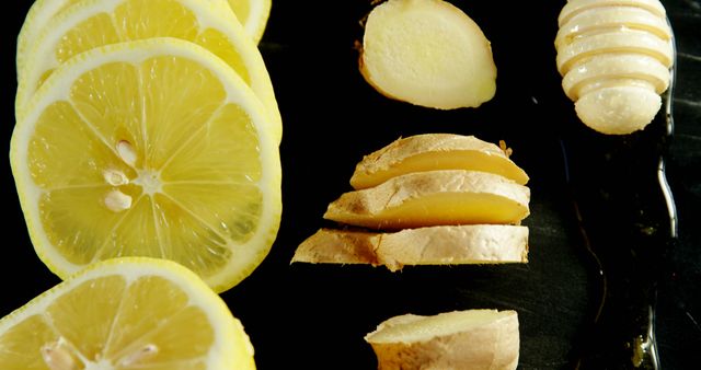 Close-up shot showing slices of lemon and ginger with honey on a dark surface. Ideal for health, wellness, food photography, and natural ingredient themes. Can be used for websites, blogs, and advertisements focusing on healthy eating or natural remedies.