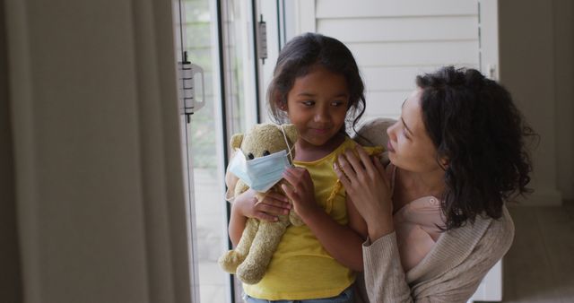 Mother comforting daughter holding teddy bear wearing mask - Download Free Stock Images Pikwizard.com