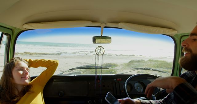 Young couple relaxing in van parked near ocean, enjoying scenic beach view. Ideal for travel blogs, summer vacation ideas, road trip stories, carefree lifestyle promotions, and adventure travel advertisements.