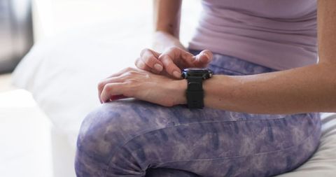Middle-aged woman checking fitness watch at home during exercise