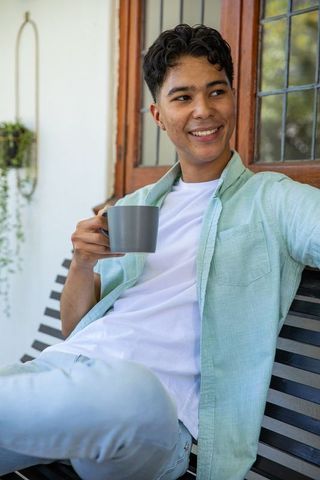 Young Man Enjoying Coffee Outdoors Relaxing on Sunny Porch