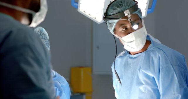 Image shows a surgeon intensely focused during an operation, surrounded by medical staff in a well-lit, sterile environment. The scene emphasizes teamwork, precision, and concentration needed during medical procedures. Useful for articles, blogs, and educational content about healthcare, surgical procedures, and the medical field.