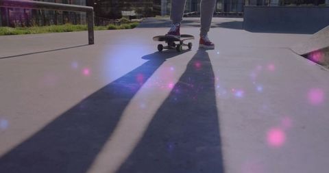 Female Skater Balancing on Skateboard at Urban Skatepark with Long Shadows and Lens Flare