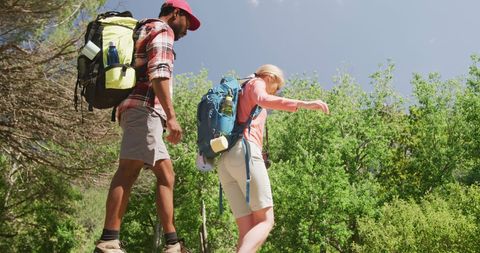 Happy Couple Hiking with Backpacks in Lush Forest