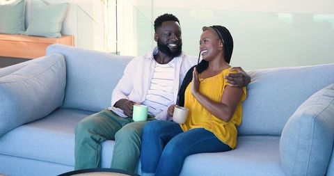 Happy couple enjoying coffee together on comfy sofa