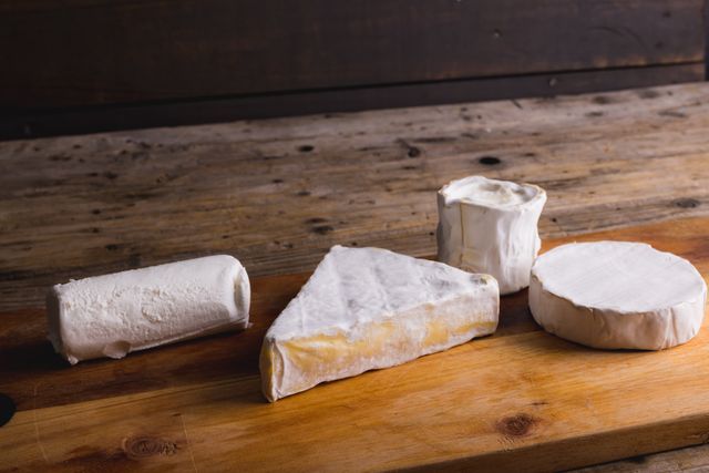 Close-up of cheese with various shaped on wooden board with copy space. unaltered, food and dairy product.