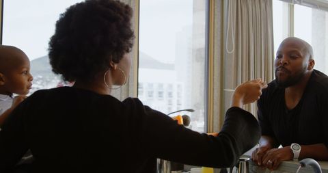 Mother Feeding Father While Holding Child in Modern Home Kitchen