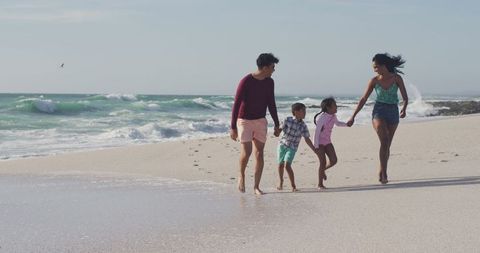 Joyful Family Strolling Hand-in-Hand on Sunny Beach - Download Free Stock Images Pikwizard.com