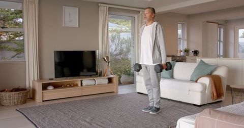 Senior Man Performing Dumbbell Workout in Living Room