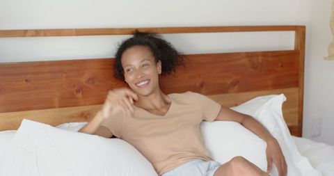 Relaxed Woman Lounging on Cozy Bed with Wooden Headboard