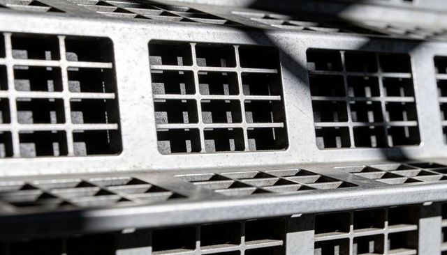 Stacked metal vent grids casting diagonal shadows showing industrial texture and scratches