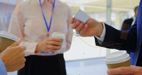 Business professionals exchanging cards over coffee during networking break at conference
