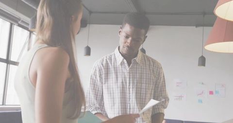 Coworkers reviewing documents in modern meeting area, collaboration and discussion