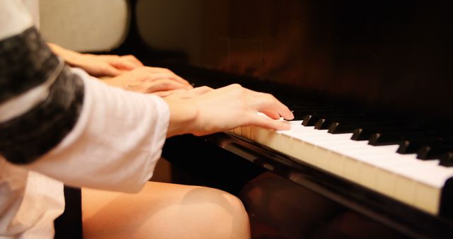 Hands of two people playing piano together, focusing on cooperation and team effort. Ideal for use in educational materials, music lessons, teamwork concepts, and articles on cooperation or musical tutorials.